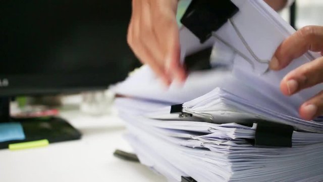 Businessman hands searching information in Stack of papers files on work in office, business report paper or piles of unfinished documents achieves with clips on offices Business concept
