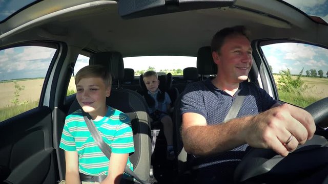 Children the boys brothers ride in the car with father male is riding in vehicle interior, cute baby caucasian kid boy in a child car seat with seat belts .Traffic along the highway