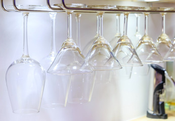 Close up on bar with wine and cocktail glasses hanging upside down in row at the nightclub