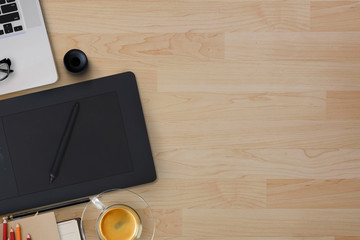 Wood modern desk table with digital drawing tablet ,laptop computer, coffee cup and supplies.