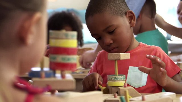 Montessori School Pupils Work At Desk With Wooden Building Set