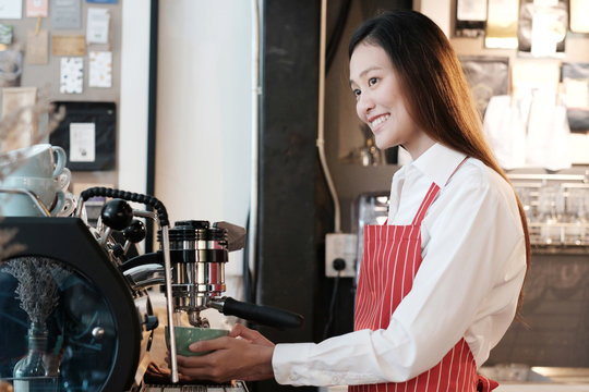 Young asian women Barista using coffee machine at counter in her cafe background, small business owner, food and drink industry concept
