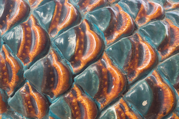 close up colorful texture of ceramic serpent scale in Thailand temple, beautiful color handmade, selective focus, elegant gentle green and red.