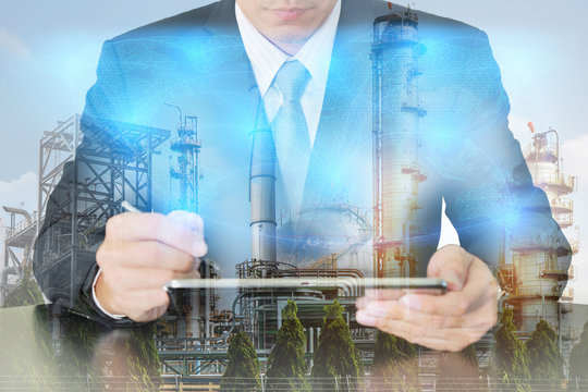 Double exposure of businessman working with tablet, digital light networking world map, Electric Generating, fuel oil Factory and Energy Industry plant at sunset as business and industrial concept.