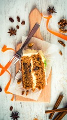 Top view of a homemade carrot cake with raisins, walnuts and cinnamon over white wooden background. Cream cheese frosting.