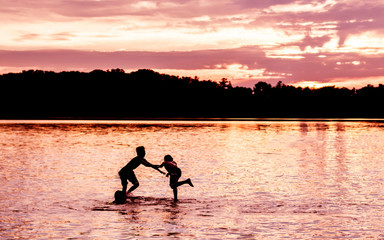 Kids and families are having fun at a lake under sunset	