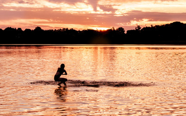 Naklejka na ściany i meble Kids and families are having fun at a lake under sunset 
