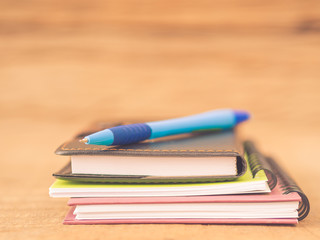 Naklejka premium Office accessories including note books and blue pen on wooden background. Education and business concept.