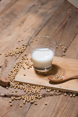 Soy milk or soya milk and soy beans in spoon on wooden table.