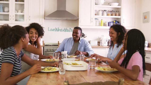 Family With Teenage Children Eating Meal In Kitchen