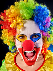 Mad clown on black background. Portrait of crazy woman is shouting loudly after performance. She hates children.