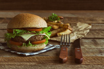 Homemade hamburger on plaid napkin with french fries. Delicious sandwich hamburger with meat or pork ham cheese and fresh vegetable. Hamburger or sandwich is the popular fast food for brunch or lunch.