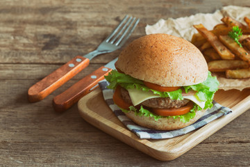 Homemade hamburger on plaid napkin with french fries. Delicious sandwich hamburger with meat or pork ham cheese and fresh vegetable. Hamburger or sandwich is the popular fast food for brunch or lunch.