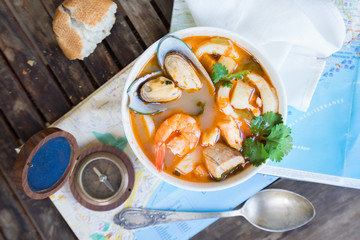 Bowl of Bouillabaisse french seafood soup with compass and mediterranean sea maps