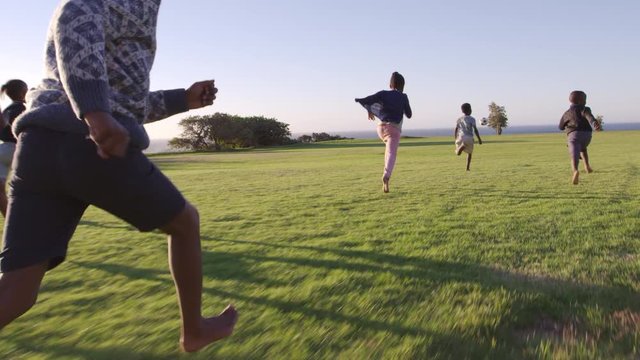 Elementary school kids chasing football in a field