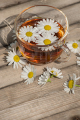 Obraz na płótnie Canvas Herbal tea with chamomile on a wooden table on a summer sunny morning