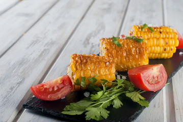 corn grilled with tomatoes and greens on a plate © vimart