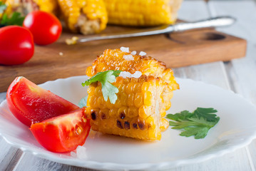 corn grilled with tomatoes and greens on a plate © vimart