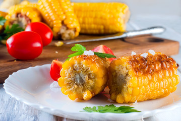 corn grilled with tomatoes and greens on a plate © vimart