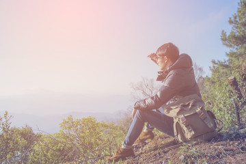 Young Man standing alone in forest outdoor with sunset nature on background Travel Lifestyle and survival concept.