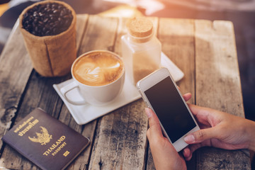 Close-up Of Woman Holding Mobile Phone In Front Of Coffee Cup