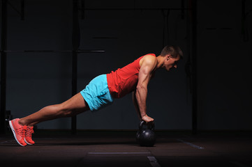 Muscular man exercising with kettle bells in gym