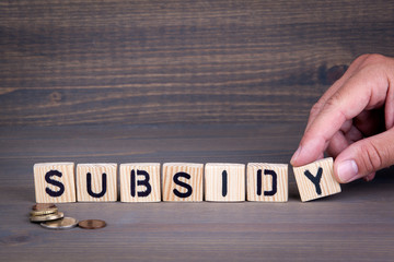 Subsiday. Wooden letters on dark background. Office desk