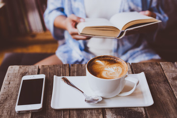 Young woman reading a book and cup of tea or coffee.