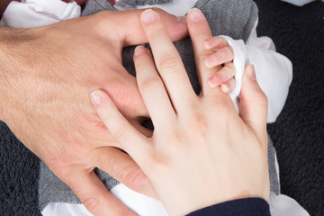 parental hand holds hand the baby