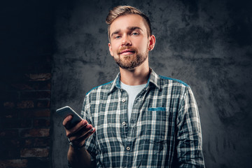 A man holds smart phone over grey background.