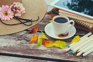 Digital tablet, books, colorfull pencils and cup of coffee on old wooden table outdoor in the park