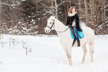 Fototapeta na wymiar Nice girl and white horse outdoor in snowfall in a winter