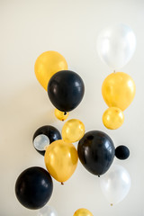 Many bright yellow white and black balloons isolated on backdrop.