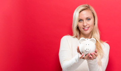 Fototapeta na wymiar Young woman with a piggy bank on a red background