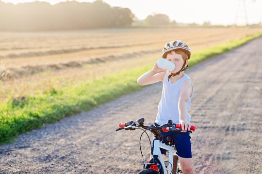 Boy in a bicycle helmet drinks bottled water