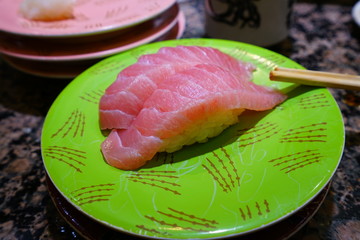 Two pieces of otoro fatty tuna sushi on a green plate
