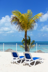 Sunbeds on the tropical paradise. Sunny and hot day by the beach.