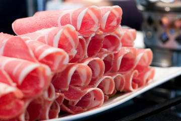 Rolls of raw pork for hot pot on a white plate