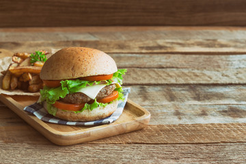 Homemade hamburger on plaid napkin with french fries. Delicious sandwich hamburger with meat or pork ham cheese and fresh vegetable. Hamburger or sandwich is the popular fast food for brunch or lunch.