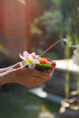 Woman holding canang sari - offering for Gods. Balinese tradition.
