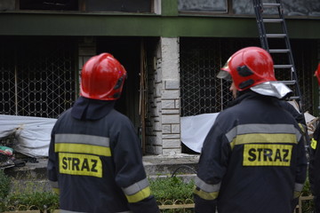 strażacy oglądający spalony budynek 