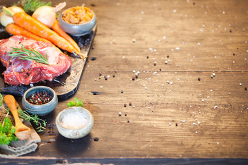 Deer or venison roast with vegetables, sea salt, red, green, white pepper and coriander in clay pots on an old black rustic table. Soup or stew preparation. Copy space 