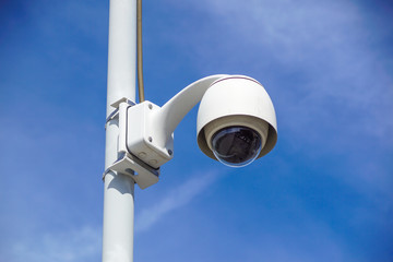 High tech overhead security camera with a gradient blue sky.