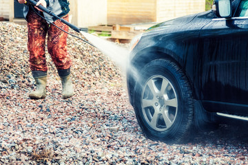 A man washes his car in the yard