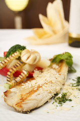 Hake fillet with grilled vegetables arranged on a plate, Traditional dish in elegant setting, Selective focus with soft light