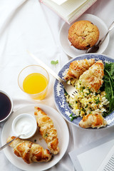 Breakfast in bed. Scrambled eggs with cheese croissants, raspberry muffin and black coffee. Morning treat concept. Composition with copy space.