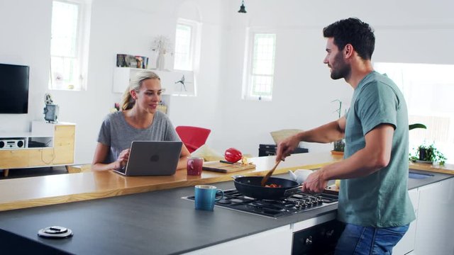 Young Couple Preparing Meal Together In Modern Kitchen