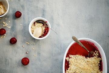Cramble Pie with plums in baking dish on light background 

