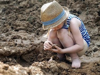 Little girl sculpts out of clay. A lot of dirt, funny baby