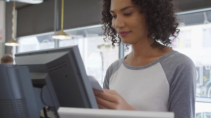 Waitress Adding Up Bill At Cash Register In Coffee Shop - Powered by Adobe